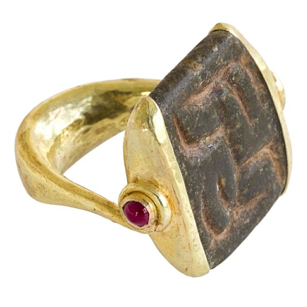 Oude zegelring met een gouden ring en houder waarin een soort houten zegel is bevestigd met vervaagde markeringen erin